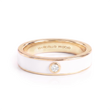 A Marcello Riccio ring featuring a white enamel band, rose gold accents, and a single round-cut clear gemstone on the front, set against a plain white background.